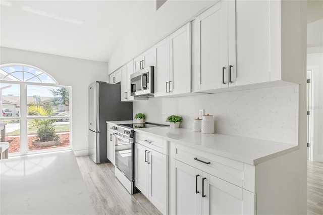 10538 Juliano Dr, Riverview, FL 33569 - kitchen featuring stainless steel appliances, light wood-style floors, white cabinetry, lofted ceiling, and light stone counters