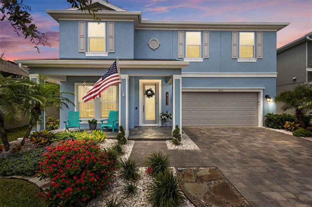 4770 Ballantrae Blvd, Land O Lakes, FL 34638 - view of front facade with a garage, stucco siding, decorative driveway, and covered porch
