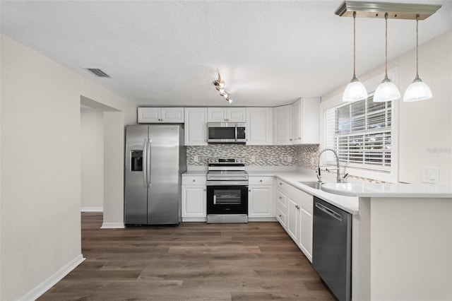 5122 Chet Dr, New Port Richey, FL 34652 - kitchen featuring appliances with stainless steel finishes, a sink, white cabinets, decorative backsplash, and a textured ceiling