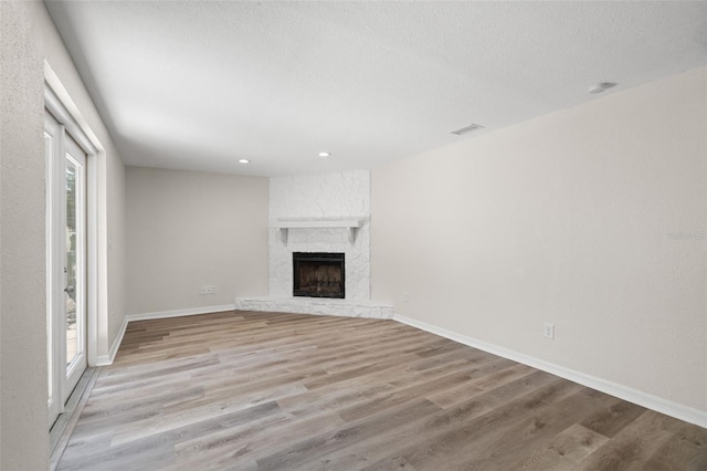 5122 Chet Dr, New Port Richey, FL 34652 - unfurnished living room featuring light wood finished floors, a stone fireplace, baseboards, recessed lighting, and a textured ceiling