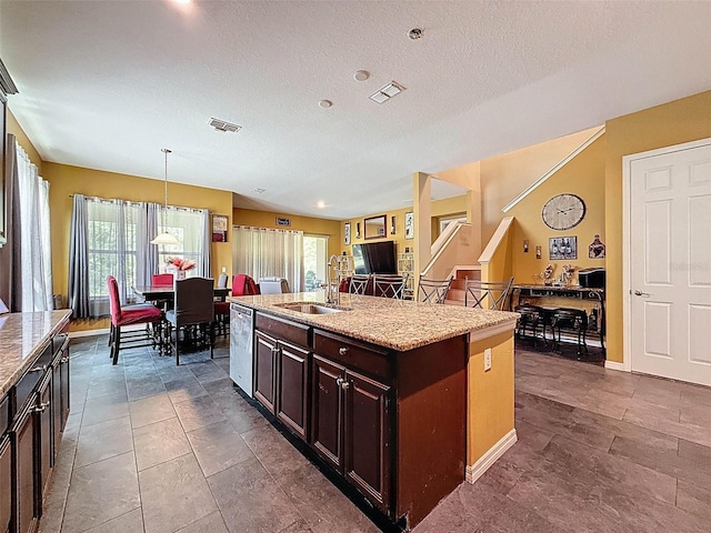 4916 Rolling Green Dr, Wesley Chapel, FL 33543 - kitchen featuring a sink, a center island with sink, hanging light fixtures, stainless steel dishwasher, and light stone countertops