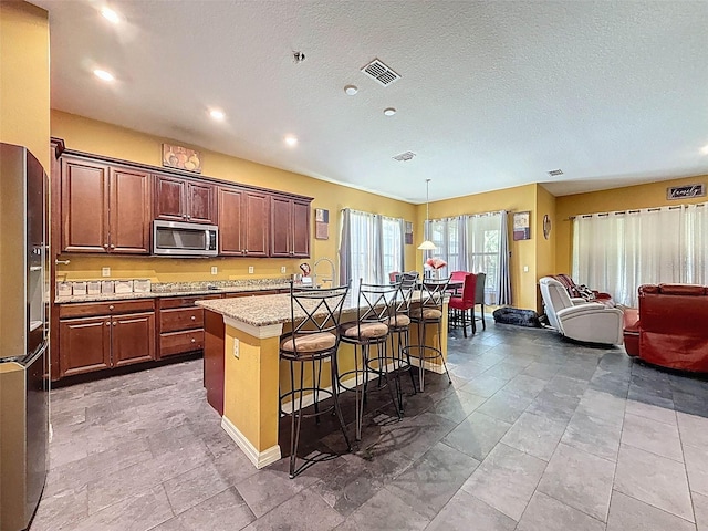 4916 Rolling Green Dr, Wesley Chapel, FL 33543 - kitchen with black fridge with ice dispenser, stainless steel microwave, a kitchen island with sink, open floor plan, and a kitchen breakfast bar