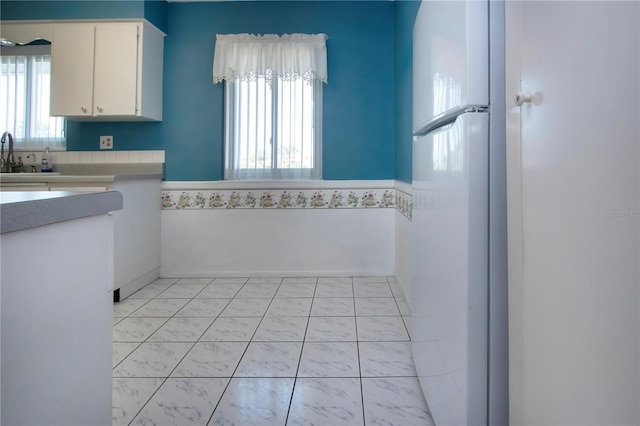 1009 Andover Cir, Sun City Center, FL 33573 - kitchen featuring plenty of natural light, light countertops, white cabinets, and light marble finish flooring