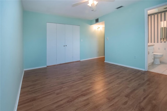 1009 Andover Cir, Sun City Center, FL 33573 - unfurnished bedroom with wood finished floors, a closet, a ceiling fan, ensuite bathroom, and baseboards