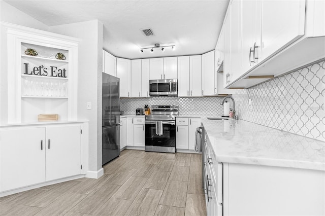 4531 7th Ave N, Saint Petersburg, FL 33713 - kitchen featuring appliances with stainless steel finishes, a sink, decorative backsplash, white cabinetry, and light wood-type flooring