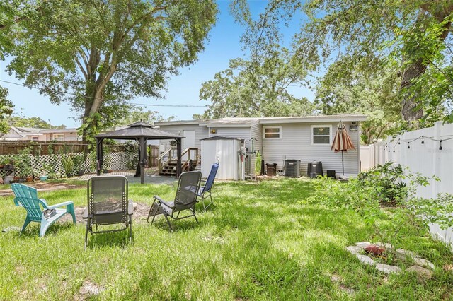 1015 13th Ave NW, Largo, FL 33770 - rear view of property with a gazebo, an outdoor fire pit, a storage unit, and a fenced backyard