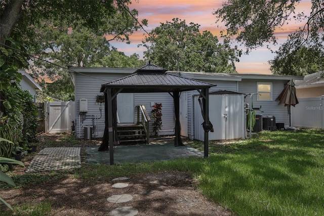 1015 13th Ave NW, Largo, FL 33770 - back of house at dusk with a gazebo, a storage shed, a patio, and a gate