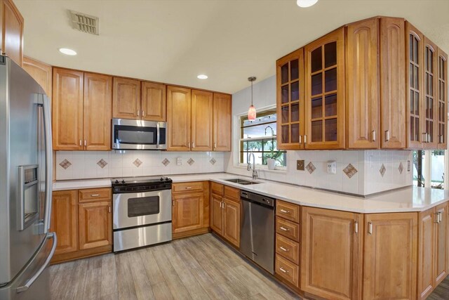 15108 Springview St, Tampa, FL 33624 - kitchen featuring stainless steel appliances, a sink, light wood-style flooring, brown cabinets, and recessed lighting