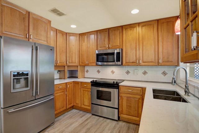 15108 Springview St, Tampa, FL 33624 - kitchen with stainless steel appliances, a sink, light wood-style floors, decorative backsplash, and recessed lighting