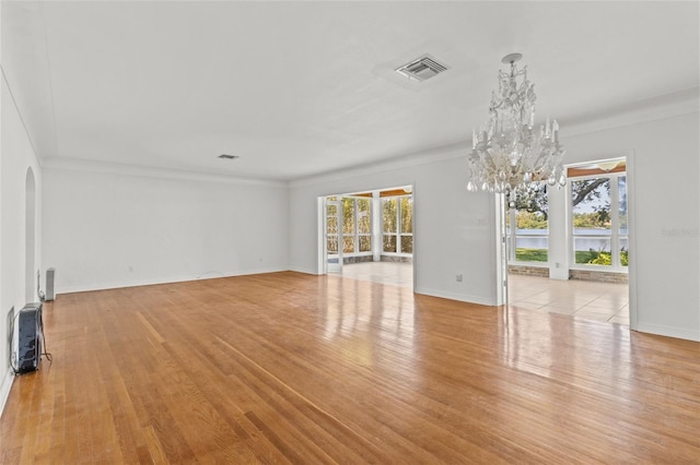 1238 Monterey Blvd NE, Saint Petersburg, FL 33704 - unfurnished living room with a chandelier, wood finished floors, arched walkways, baseboards, and crown molding