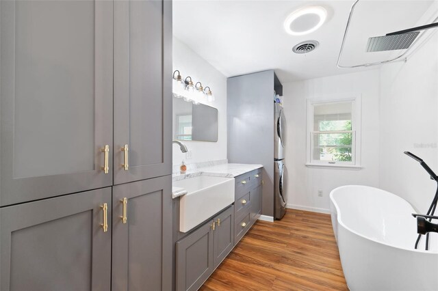 509 Falmouth St, Temple Terrace, FL 33617 - bathroom with stacked washer / drying machine, vanity, wood finished floors, a freestanding tub, and baseboards