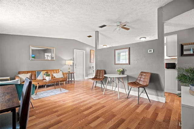 4150 Pecos Dr, New Port Richey, FL 34653 - living area featuring wood finished floors, vaulted ceiling, a ceiling fan, a textured ceiling, and baseboards