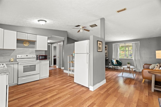 4150 Pecos Dr, New Port Richey, FL 34653 - kitchen with white appliances, light wood-style floors, white cabinets, ceiling fan, and decorative backsplash