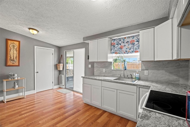 4150 Pecos Dr, New Port Richey, FL 34653 - kitchen featuring electric range, light wood-style flooring, tasteful backsplash, light countertops, and a textured ceiling