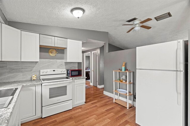 4150 Pecos Dr, New Port Richey, FL 34653 - kitchen with white appliances, a ceiling fan, vaulted ceiling, light wood-style floors, and white cabinetry