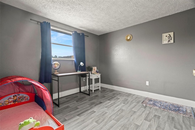 4150 Pecos Dr, New Port Richey, FL 34653 - bedroom featuring wood finished floors, a textured ceiling, and baseboards