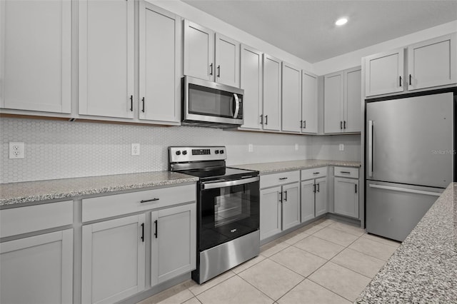12697 Achasta Blvd, Hudson, FL 34669 - kitchen with stainless steel appliances, light tile patterned flooring, decorative backsplash, light stone counters, and recessed lighting