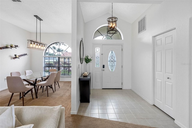 12470 93rd St, Largo, FL 33773 - foyer entrance with a chandelier, vaulted ceiling, light tile patterned floors, a textured ceiling, and light colored carpet