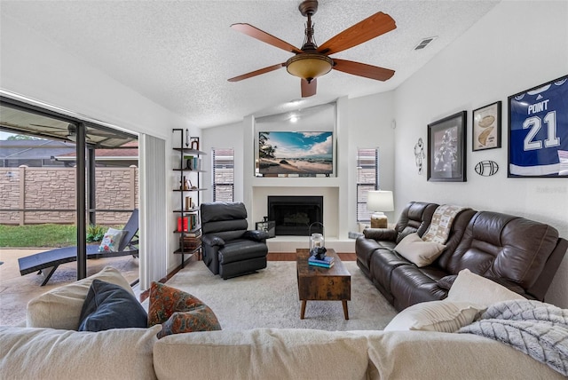 12470 93rd St, Largo, FL 33773 - living area with a ceiling fan, vaulted ceiling, a textured ceiling, and a fireplace with raised hearth