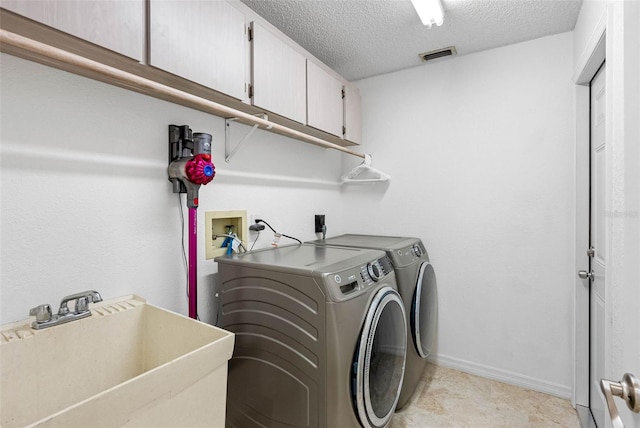 12470 93rd St, Largo, FL 33773 - laundry area featuring cabinet space, washer and clothes dryer, a textured ceiling, and baseboards