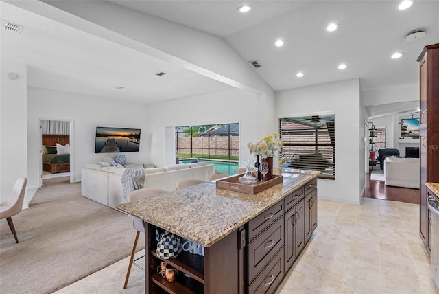 12470 93rd St, Largo, FL 33773 - kitchen with recessed lighting, a center island, light stone counters, lofted ceiling, and light carpet