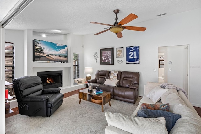 12470 93rd St, Largo, FL 33773 - living area with a textured ceiling, a warm lit fireplace, a ceiling fan, healthy amount of natural light, and lofted ceiling