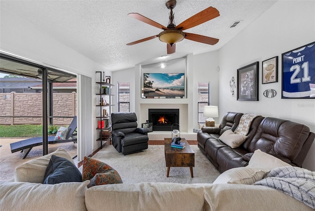 12470 93rd St, Largo, FL 33773 - living room with a ceiling fan, a textured ceiling, vaulted ceiling, a warm lit fireplace, and wood finished floors