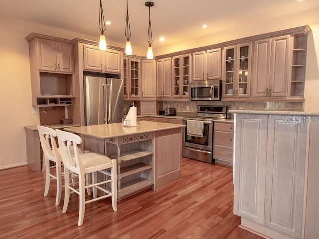 101 8th St, Belleair Beach, FL 33786 - kitchen featuring open shelves, appliances with stainless steel finishes, backsplash, a kitchen island, and light wood-type flooring