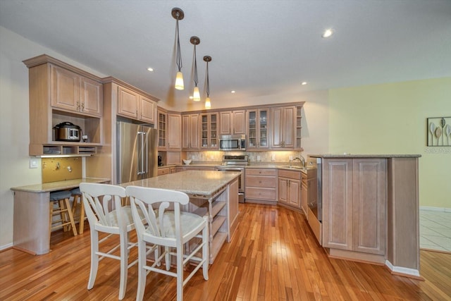 101 8th St, Belleair Beach, FL 33786 - kitchen featuring appliances with stainless steel finishes, a kitchen breakfast bar, light wood finished floors, a sink, and recessed lighting