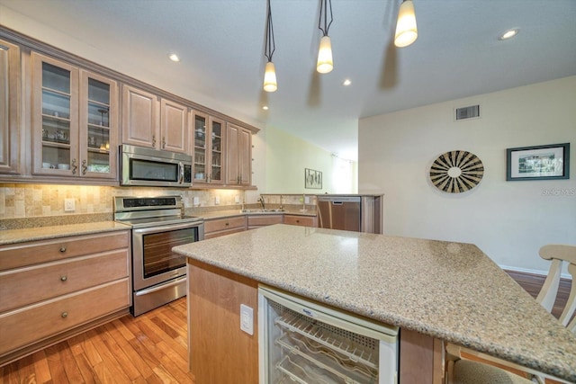 101 8th St, Belleair Beach, FL 33786 - kitchen featuring appliances with stainless steel finishes, beverage cooler, light wood-style flooring, a sink, and light stone countertops