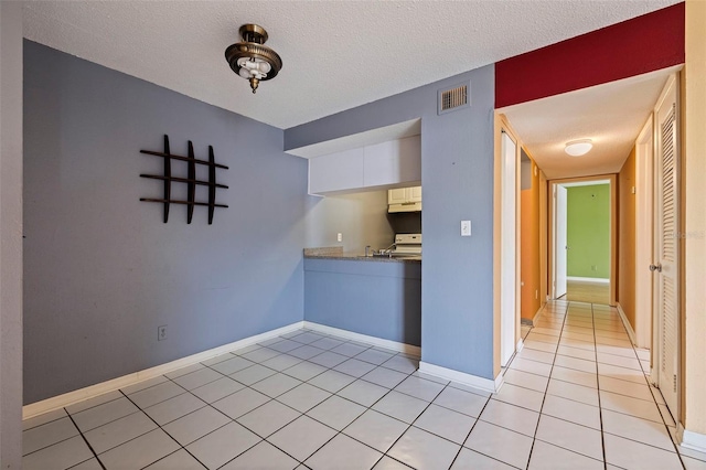 1799 N Highland Ave Unit 3, Clearwater, FL 33755 - kitchen featuring range with electric cooktop, light tile patterned floors, a textured ceiling, baseboards, and under cabinet range hood