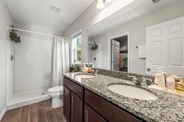 8009 N Primrose Dr, Citrus Springs, FL 34434 - bathroom with tiled shower, toilet, double vanity, wood finished floors, and a walk in closet