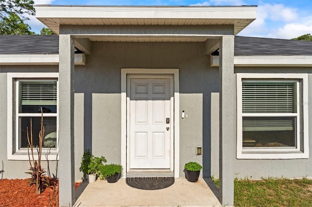 8009 N Primrose Dr, Citrus Springs, FL 34434 - doorway to property featuring roof with shingles and stucco siding