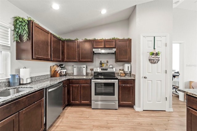 8009 N Primrose Dr, Citrus Springs, FL 34434 - kitchen with stainless steel appliances, under cabinet range hood, vaulted ceiling, light wood finished floors, and light stone counters
