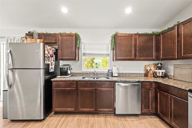8009 N Primrose Dr, Citrus Springs, FL 34434 - kitchen featuring appliances with stainless steel finishes, a sink, light wood-type flooring, stone counters, and dark brown cabinets
