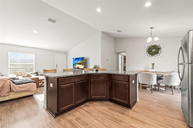 8009 N Primrose Dr, Citrus Springs, FL 34434 - kitchen featuring freestanding refrigerator, lofted ceiling, open floor plan, light stone countertops, and light wood-style flooring