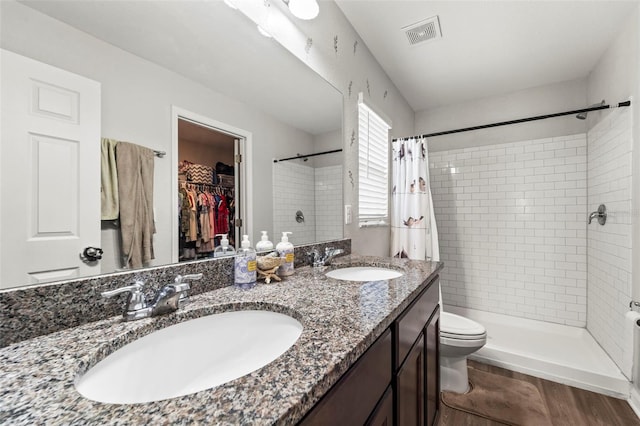 7839 N Quibble Ave, Citrus Springs, FL 34434 - full bath with a tile shower, double vanity, toilet, a walk in closet, and wood finished floors