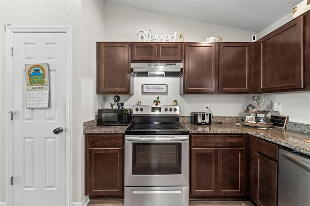 7839 N Quibble Ave, Citrus Springs, FL 34434 - kitchen featuring under cabinet range hood, appliances with stainless steel finishes, vaulted ceiling, dark brown cabinets, and dark stone counters