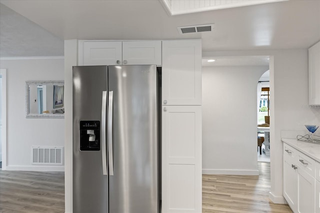2900 Sandpiper Pl, Clearwater, FL 33762 - kitchen with stainless steel fridge with ice dispenser, light wood finished floors, white cabinets, baseboards, and arched walkways