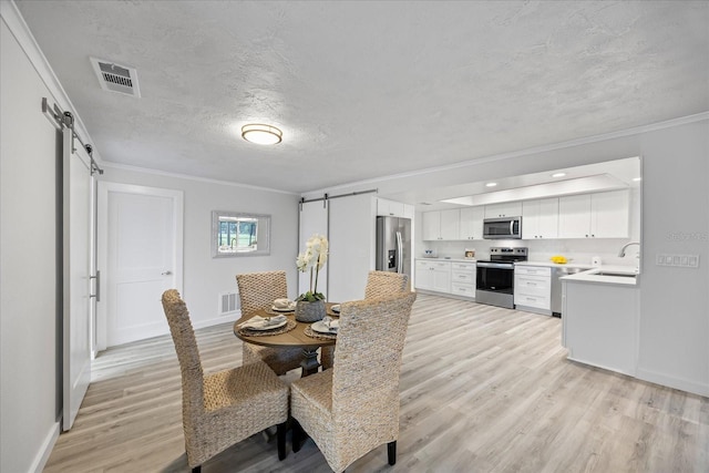 2900 Sandpiper Pl, Clearwater, FL 33762 - dining space featuring a barn door, light wood-style flooring, baseboards, a textured ceiling, and crown molding