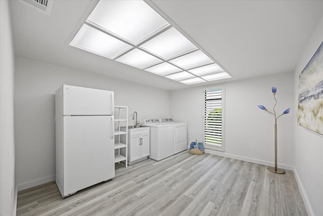 2900 Sandpiper Pl, Clearwater, FL 33762 - washroom featuring cabinet space, washer and dryer, light wood finished floors, and baseboards