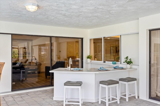 2900 Sandpiper Pl, Clearwater, FL 33762 - kitchen featuring a kitchen breakfast bar, light countertops, a textured ceiling, a sink, and a peninsula