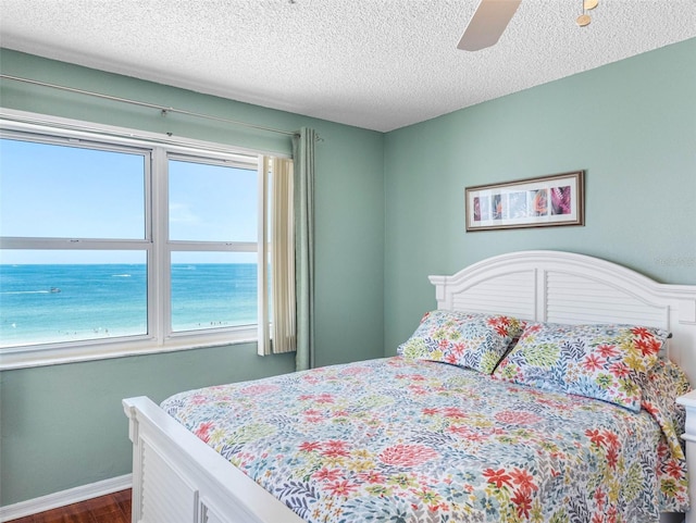 13500 Gulf Blvd Unit 506, Madeira Beach, FL 33708 - bedroom with a textured ceiling, dark wood-style flooring, ceiling fan, and a water view