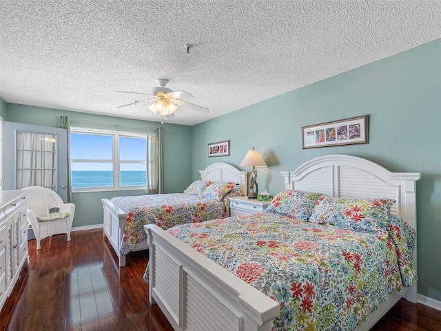 13500 Gulf Blvd Unit 506, Madeira Beach, FL 33708 - bedroom featuring dark wood-style flooring, baseboards, a ceiling fan, and a textured ceiling