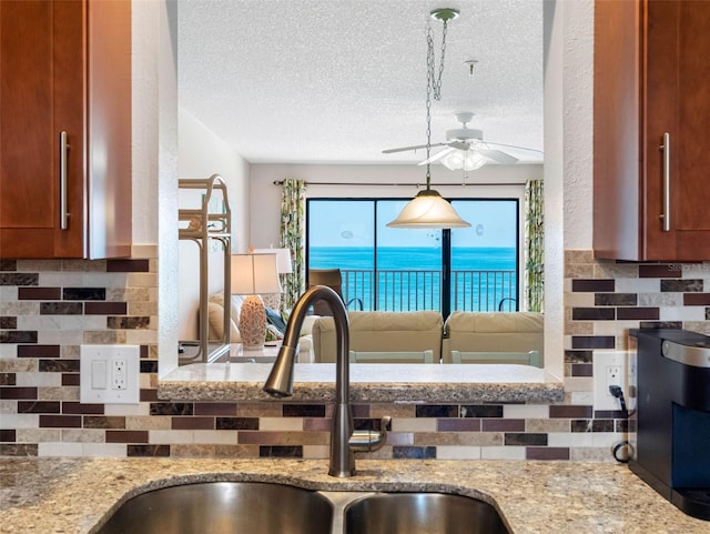 13500 Gulf Blvd Unit 506, Madeira Beach, FL 33708 - kitchen featuring a sink, ceiling fan, tasteful backsplash, and a textured ceiling