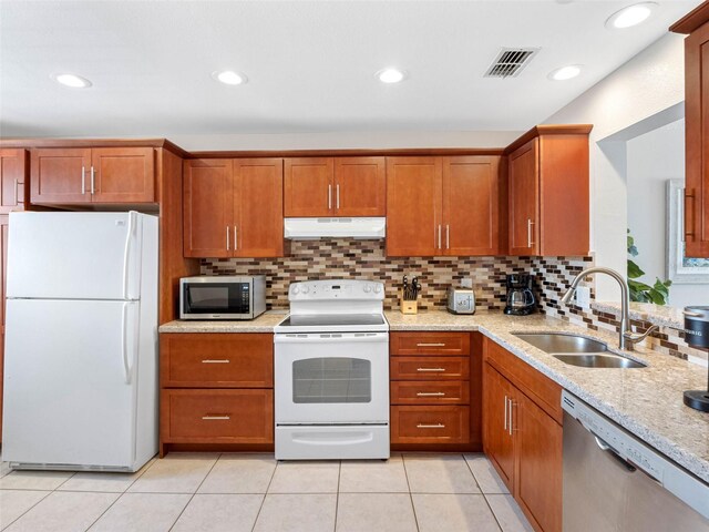 13500 Gulf Blvd Unit 506, Madeira Beach, FL 33708 - kitchen featuring stainless steel appliances, a sink, under cabinet range hood, brown cabinetry, and decorative backsplash