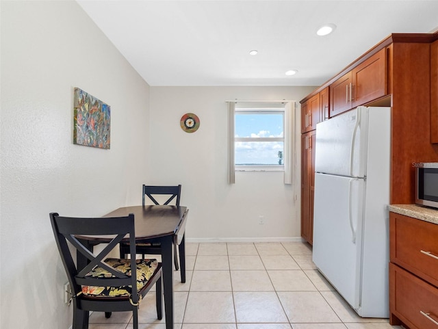13500 Gulf Blvd Unit 506, Madeira Beach, FL 33708 - kitchen featuring freestanding refrigerator, stainless steel microwave, brown cabinets, recessed lighting, and light tile patterned flooring