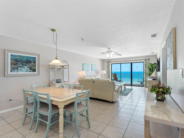 13500 Gulf Blvd Unit 506, Madeira Beach, FL 33708 - dining room with light tile patterned floors, a ceiling fan, a textured ceiling, and baseboards