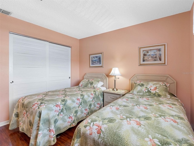 13500 Gulf Blvd Unit 506, Madeira Beach, FL 33708 - bedroom featuring dark wood-type flooring, a closet, baseboards, and a textured ceiling