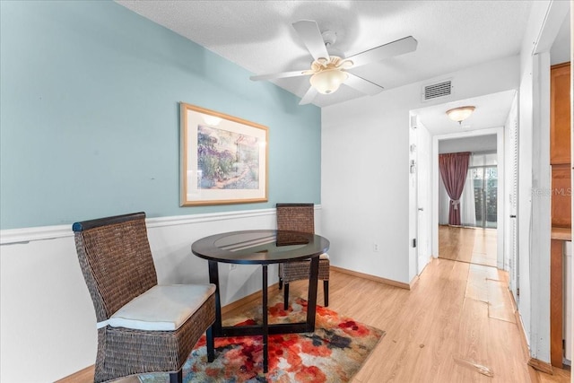2630 Pearce Dr Unit 108, Clearwater, FL 33764 - sitting room featuring light wood-type flooring, a ceiling fan, a wainscoted wall, and a textured ceiling